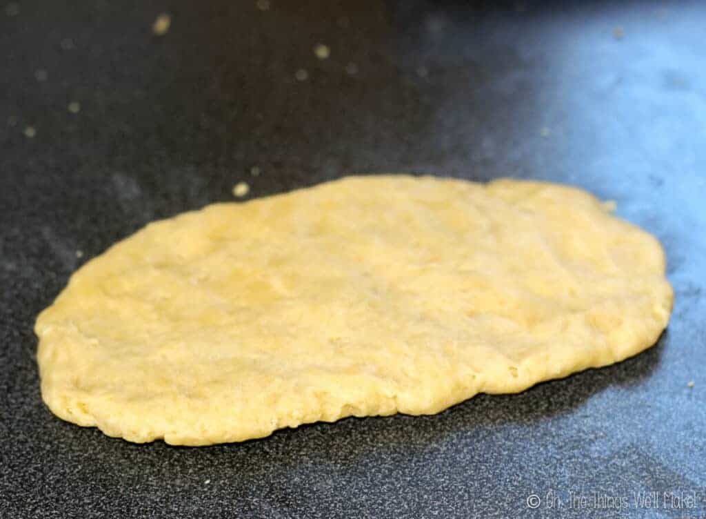 pasta dough that has been pressed into a disk shape on a counter, ready for running through a pasta machine