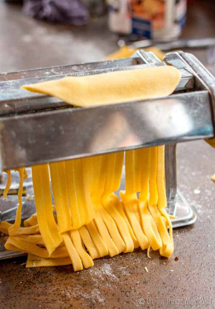 Cutting the homemade pasta dough into fettuccine using a pasta maker cutting attachment