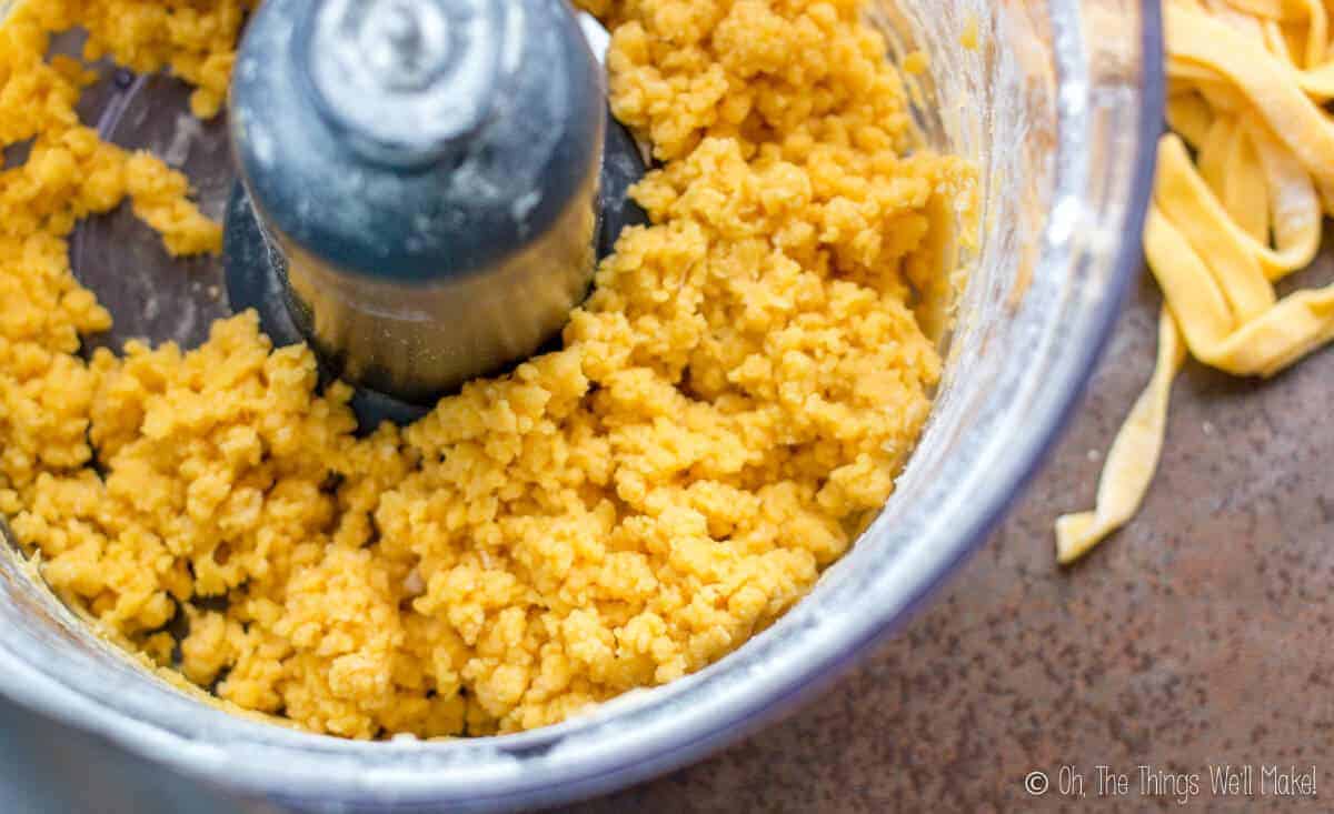 Closeup of a homemade pasta dough that is being made in the food processor showing the desired, big crumb texture.