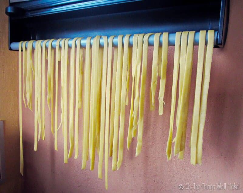 homemade fettuccini being hung over a bar for drying.