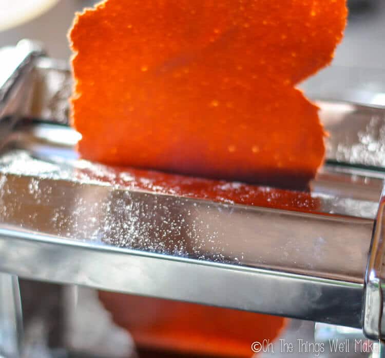 Chocolate pasta dough being run through the pasta roller.