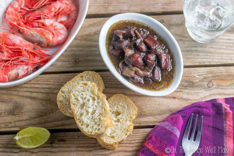 Calamares al vino tinto, or red wine braised squid, as seen from above served with bread and red prawns