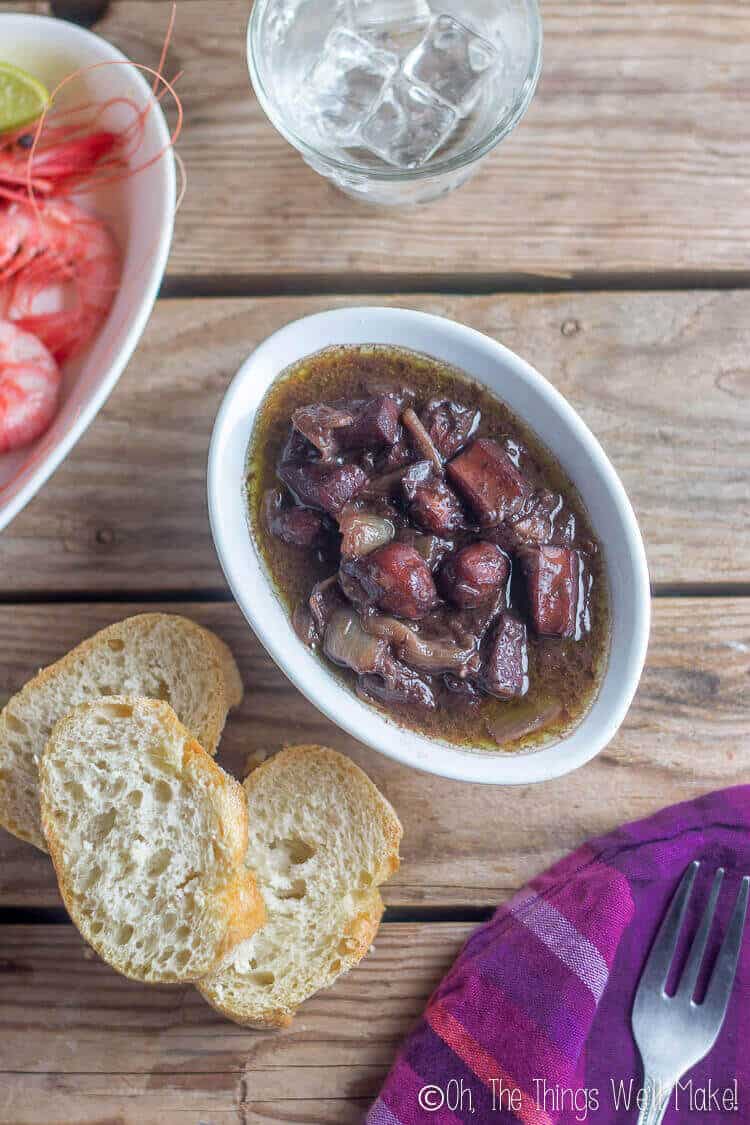 closeup of red wine braised squid and baguette bread.