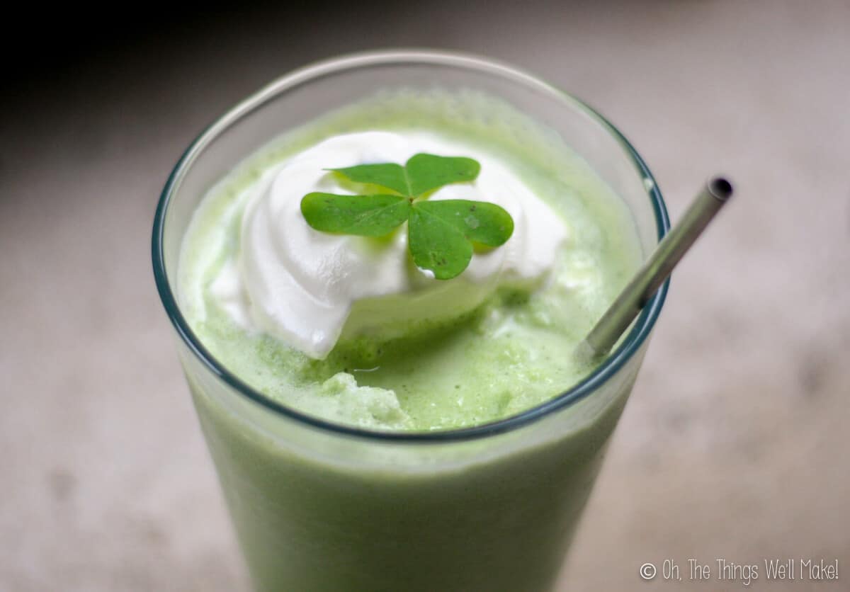 Overhead view of homemade shamrock shake topped with whipped cream, shamrock, and served with a stainless steel straw