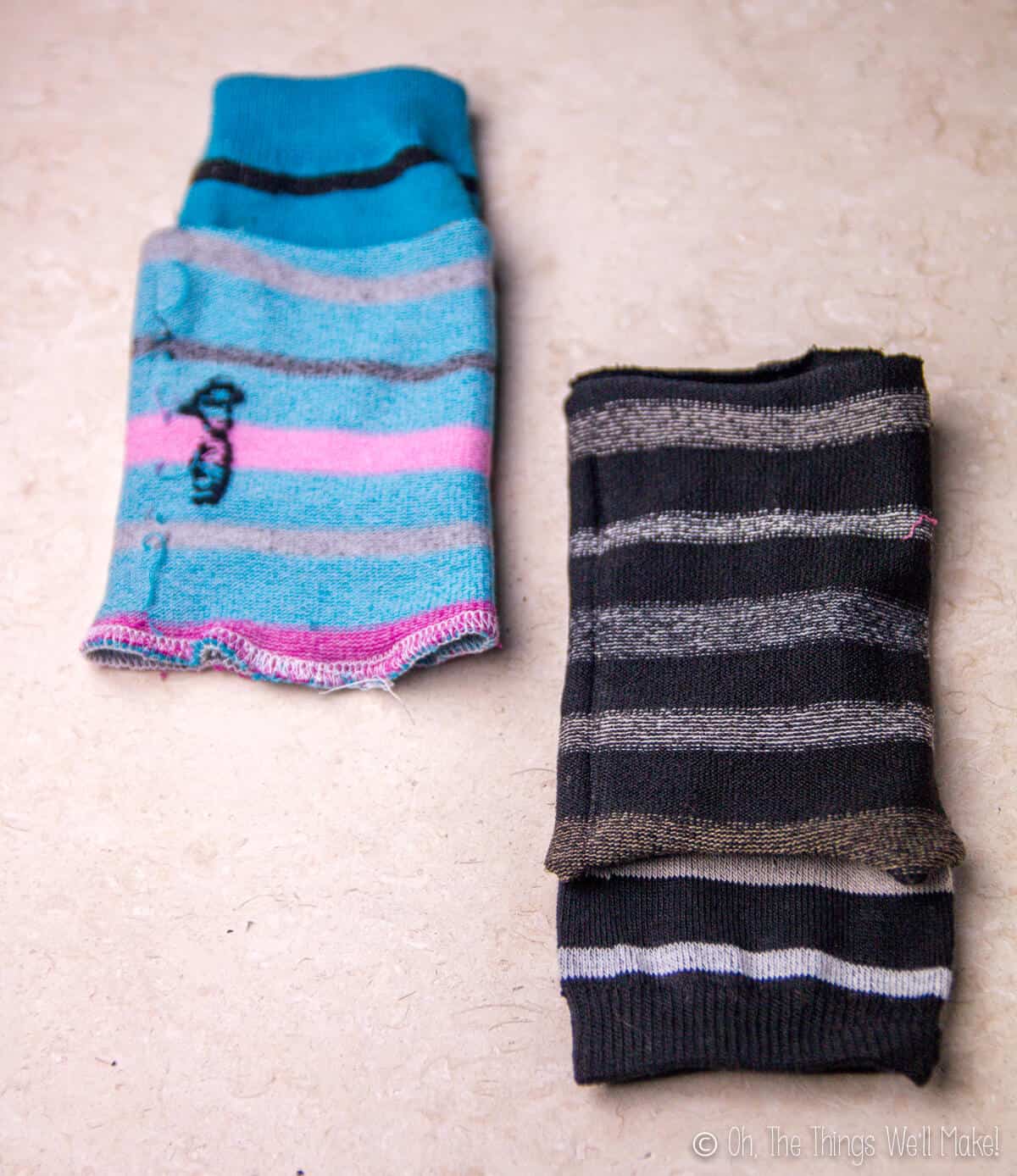 Two sock pieces, one striped blue and one black striped, put together with right sides facing in, ready to be sewn.