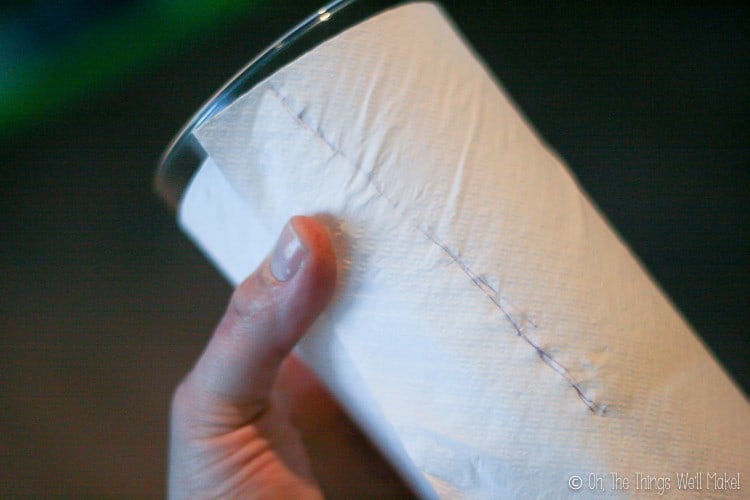 Wrapping paper around a glass to use as a pattern for a polar fleece cup cozy.