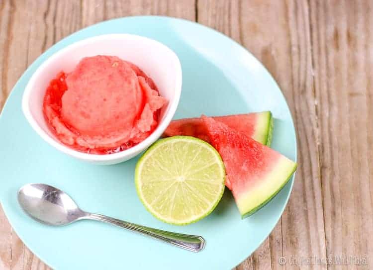 Overhead view of a small bowl of watermelon sorbet with a couple of slices of watermelon and a lime slice.