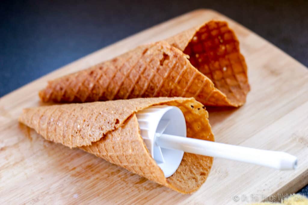 Two homemade waffle cones, one still around a cone former.