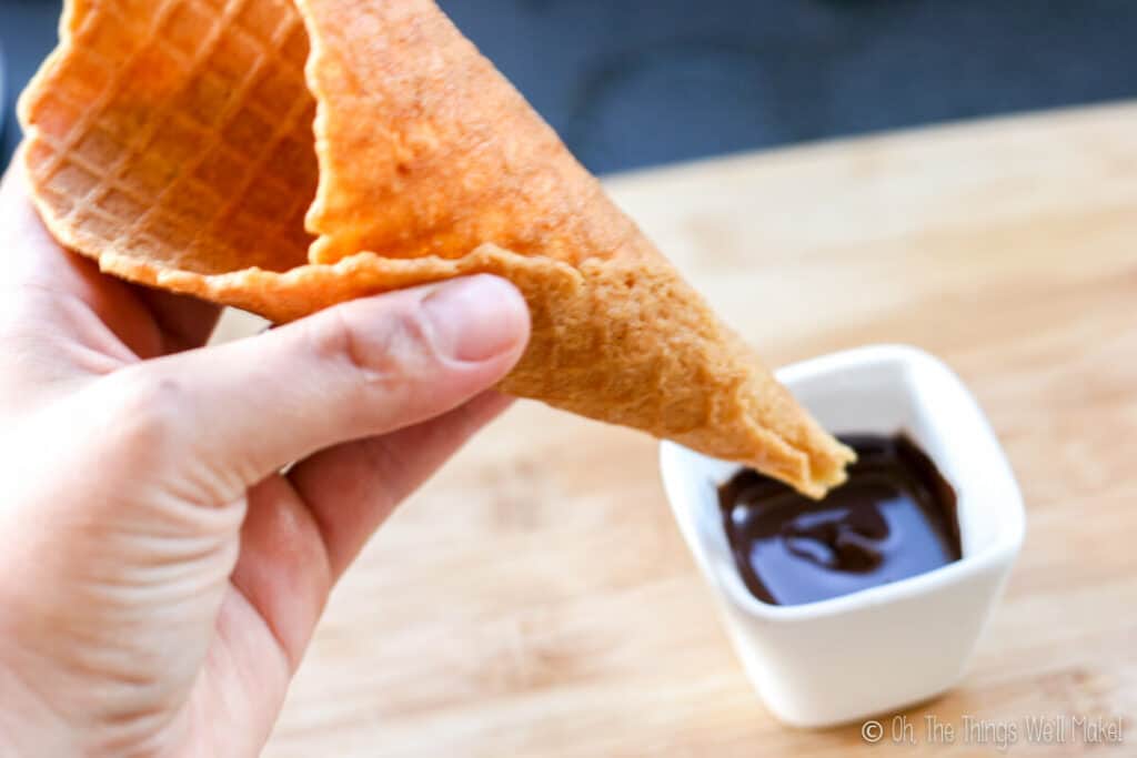 Dipping the tip of a homemade waffle cone into melted chocolate.