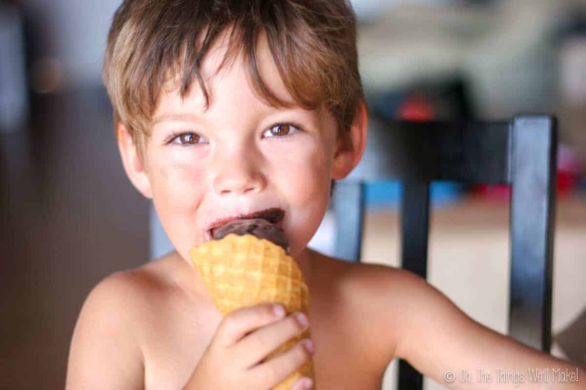 A boy eating a chocolate ice cream cone in homemade waffle cone.