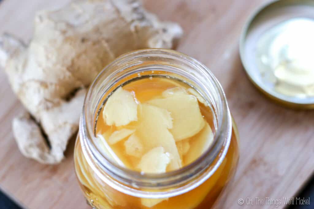 Overhead view of a glass jar filled with sliced ginger in vinegar.