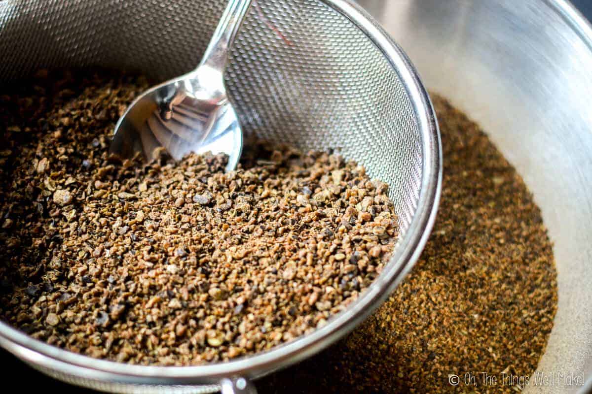 Sifting ground up carob pods through a strainer