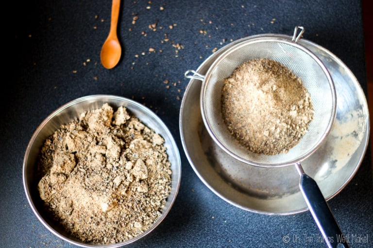 Overhead view of carob flour being sifted with a metal strainer
