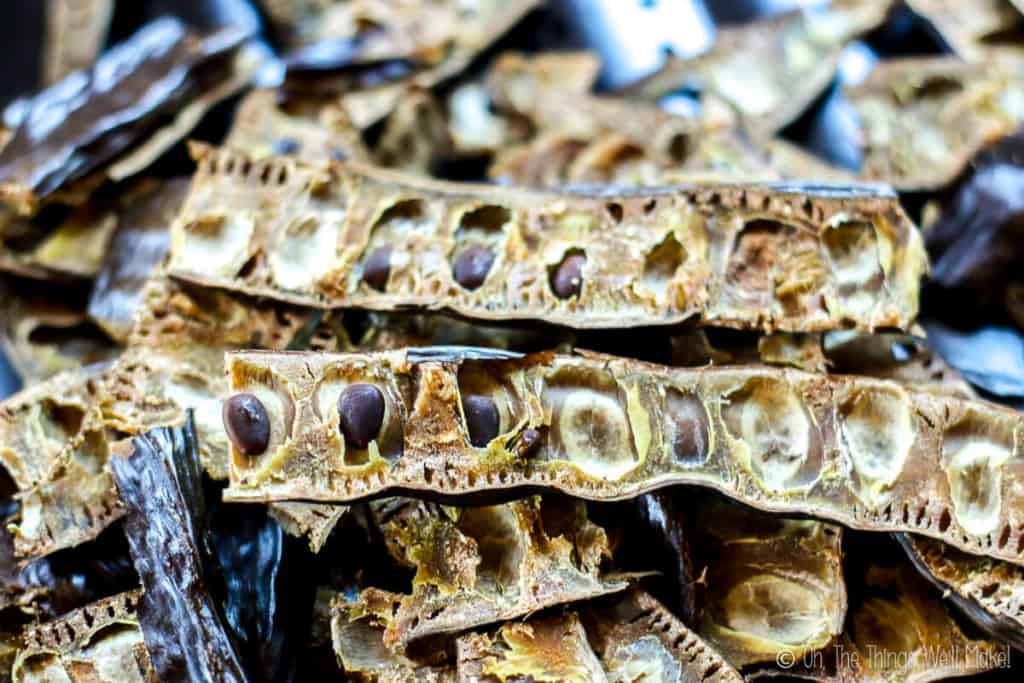 carob pods that have been sliced in half lengthwise, exposing the seeds inside of them.
