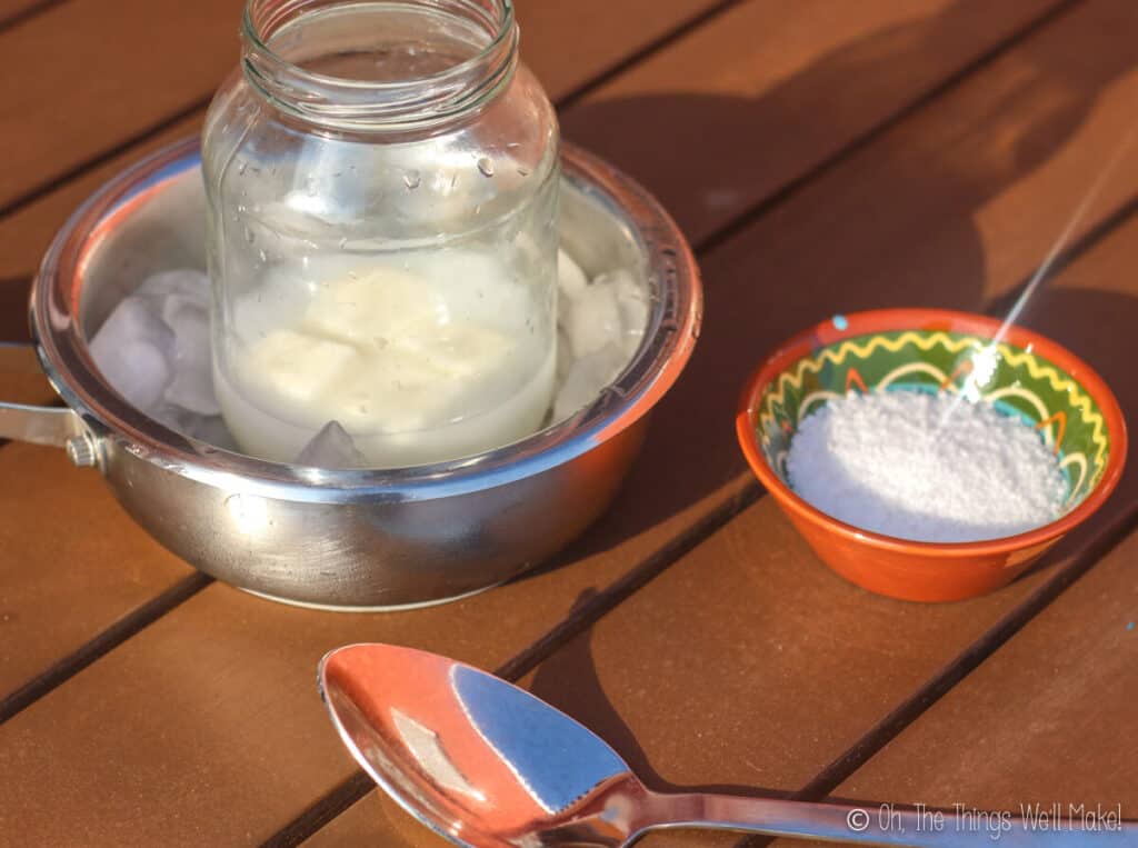 A bowl of lye next to a pan filled with ice cubes with a jar with frozen milk cubes and water in it.