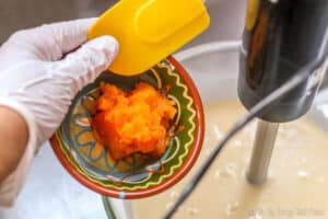 pumpkin puree being poured into a bowl with a soap mixture below.