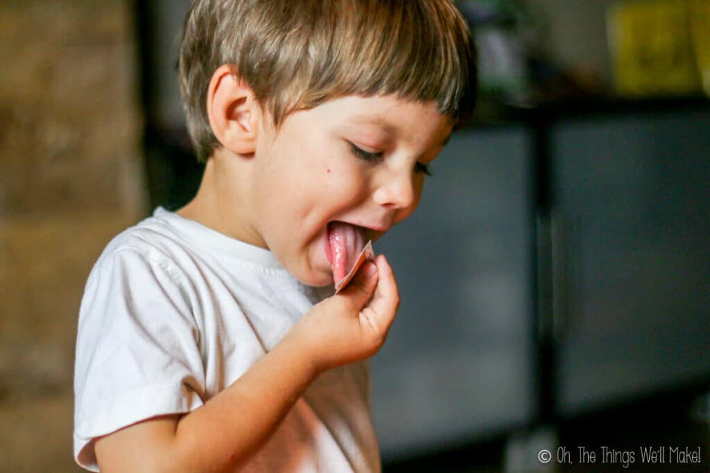 A small boy licking a homemade postage stamp