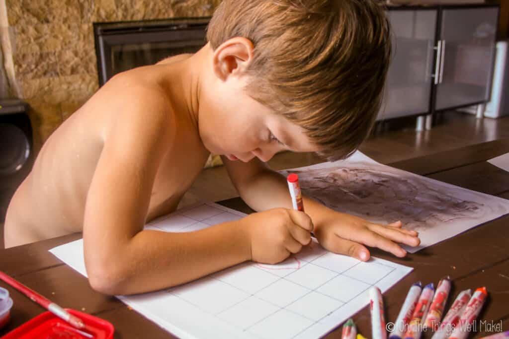 a small boy making small drawings for homemade postage stamps.