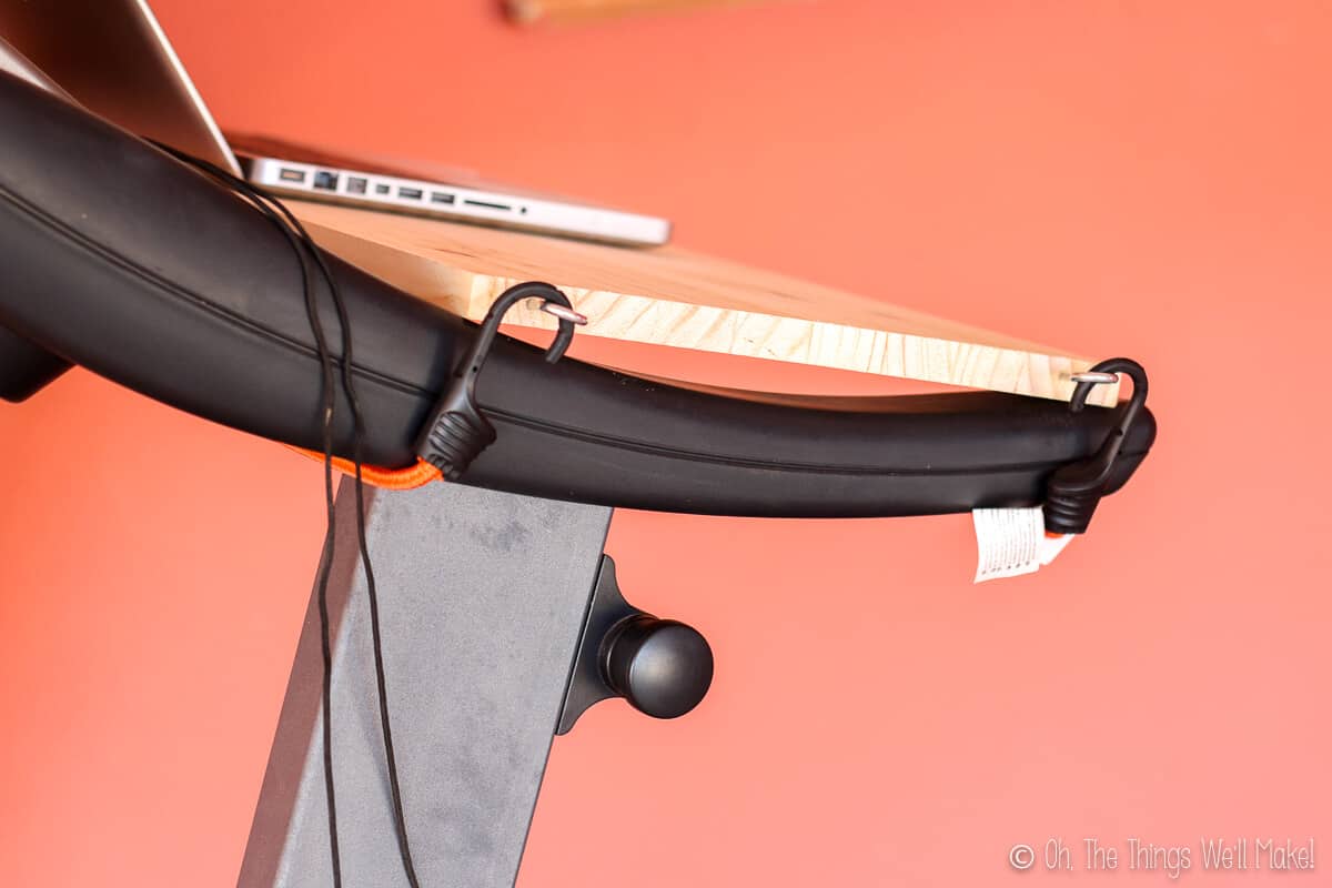 Closeup of the side view of a homemade treadmill desk showing how the bungee cords fit into the o rings