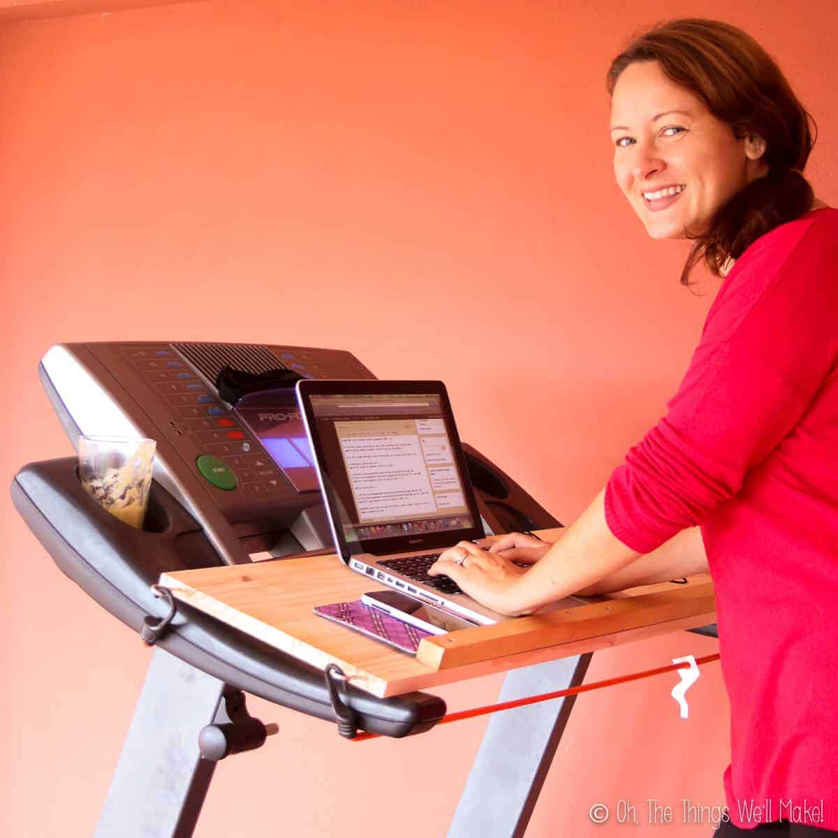 A girl on a treadmill writing on a computer on a removable desk on the treadmill