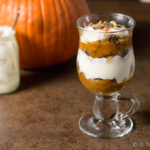 A pumpkin spice parfait in front of a jar of yogurt and a pumpkin