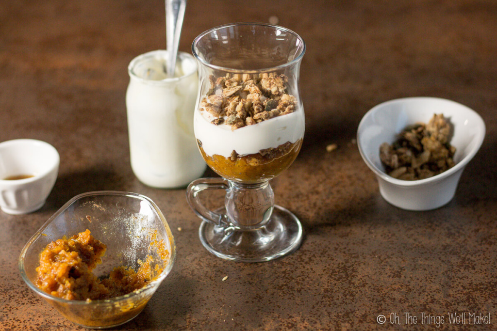 layering pumpkin puree, yogurt, and granola in a parfait glass
