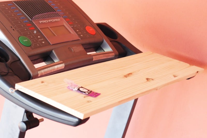 A wooden board across the handrails of a treadmill