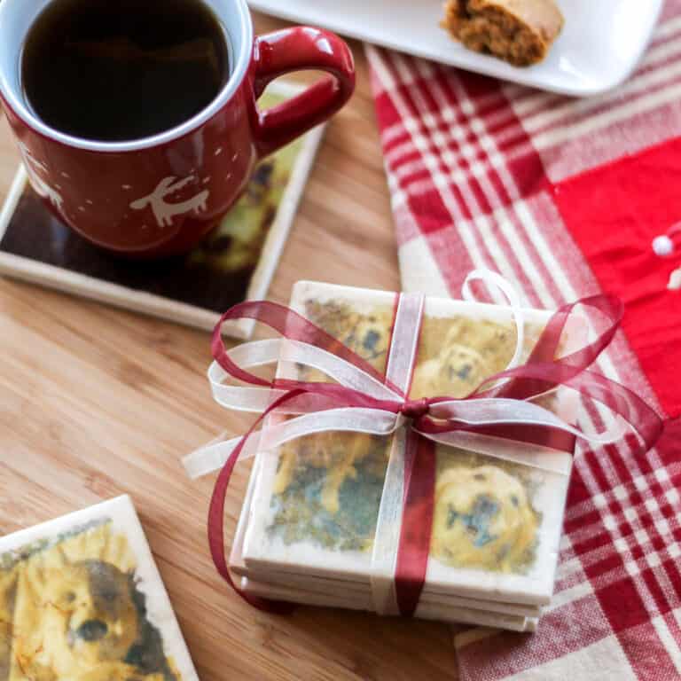 A stack of homemade marble photo coasters wrapped with organza ribbons for gifting placed beside a cup of coffee that's on top of a homemade marble photo coaster.