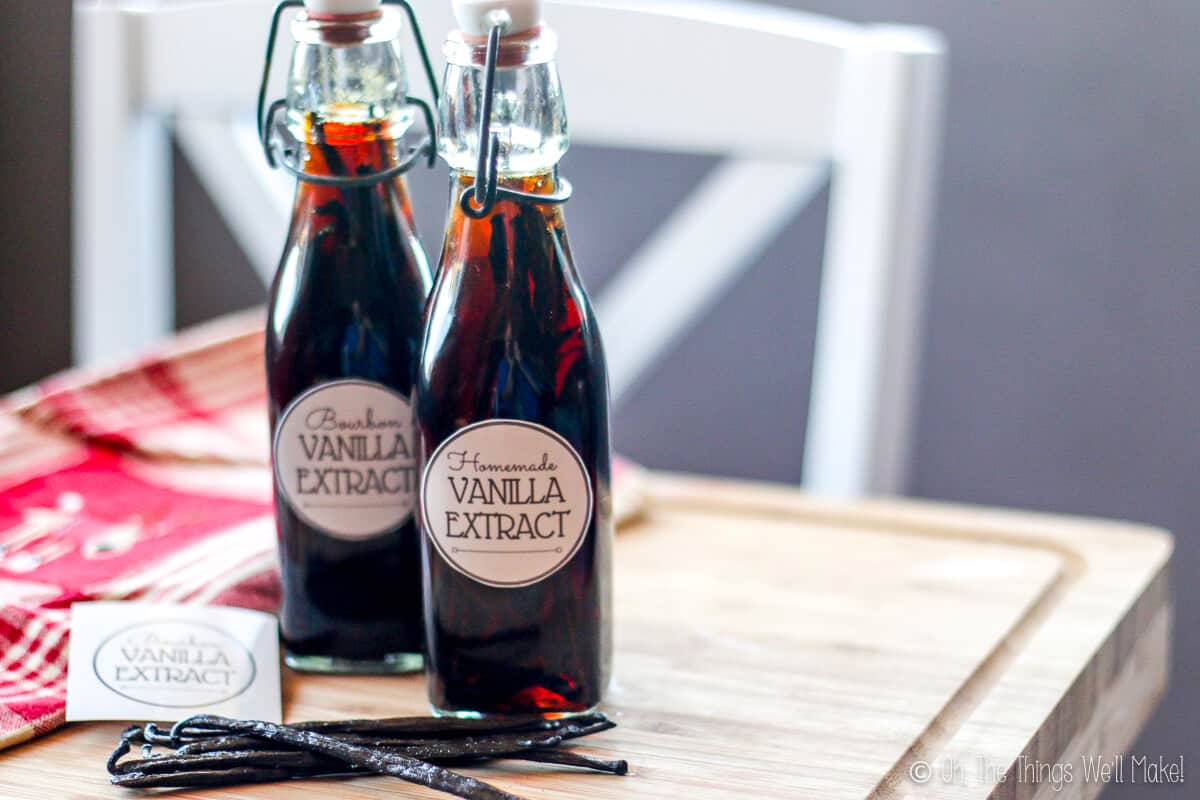 Two bottles of homemade vanilla extract with vanilla beans next to them.