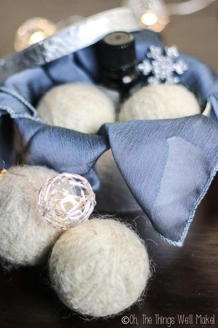 4 wool dryer balls, two of which are in a box decorated for gifting