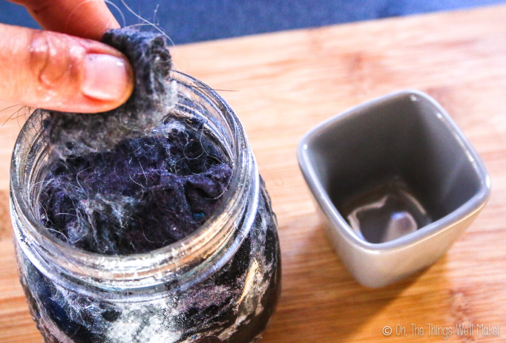 Picking up a small amount of oil saturated dryer lint from a glass jar