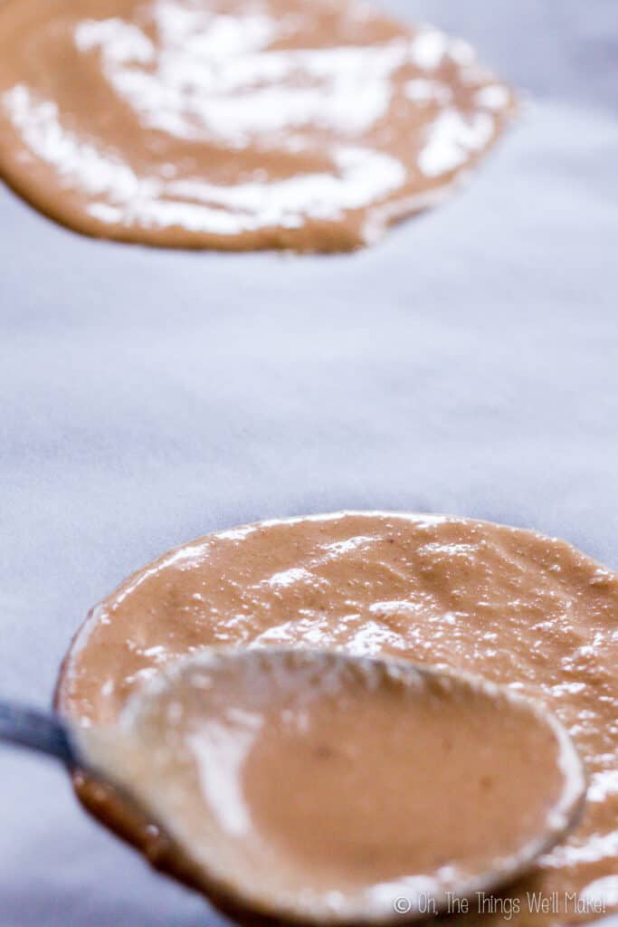 Spooning on some batter into round circle shapes onto a paper lined baking sheet