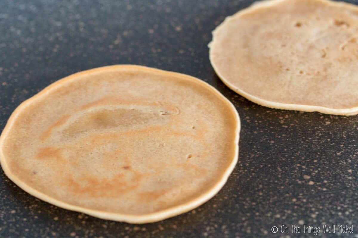 Cooking rounds of dough on a skillet for making homemade fortune cookies.