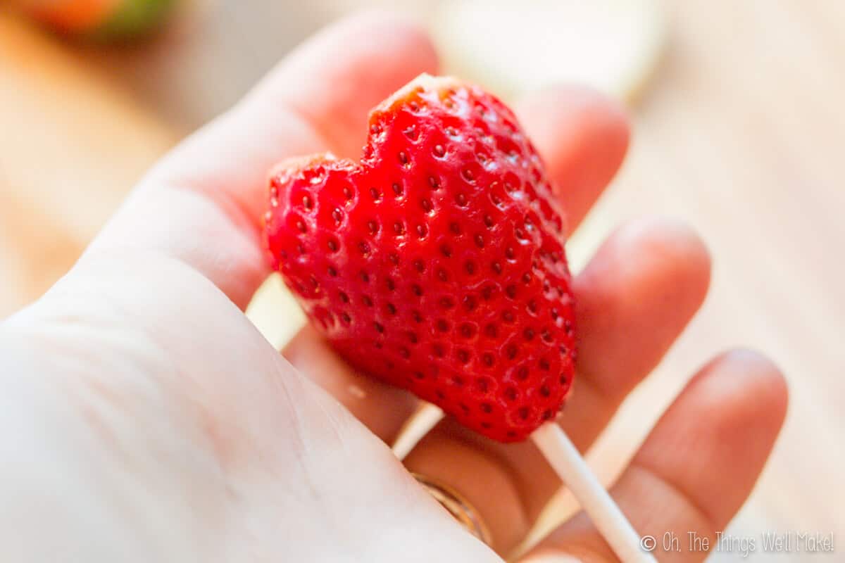 adding a skewer to the bottom of a strawberry heart