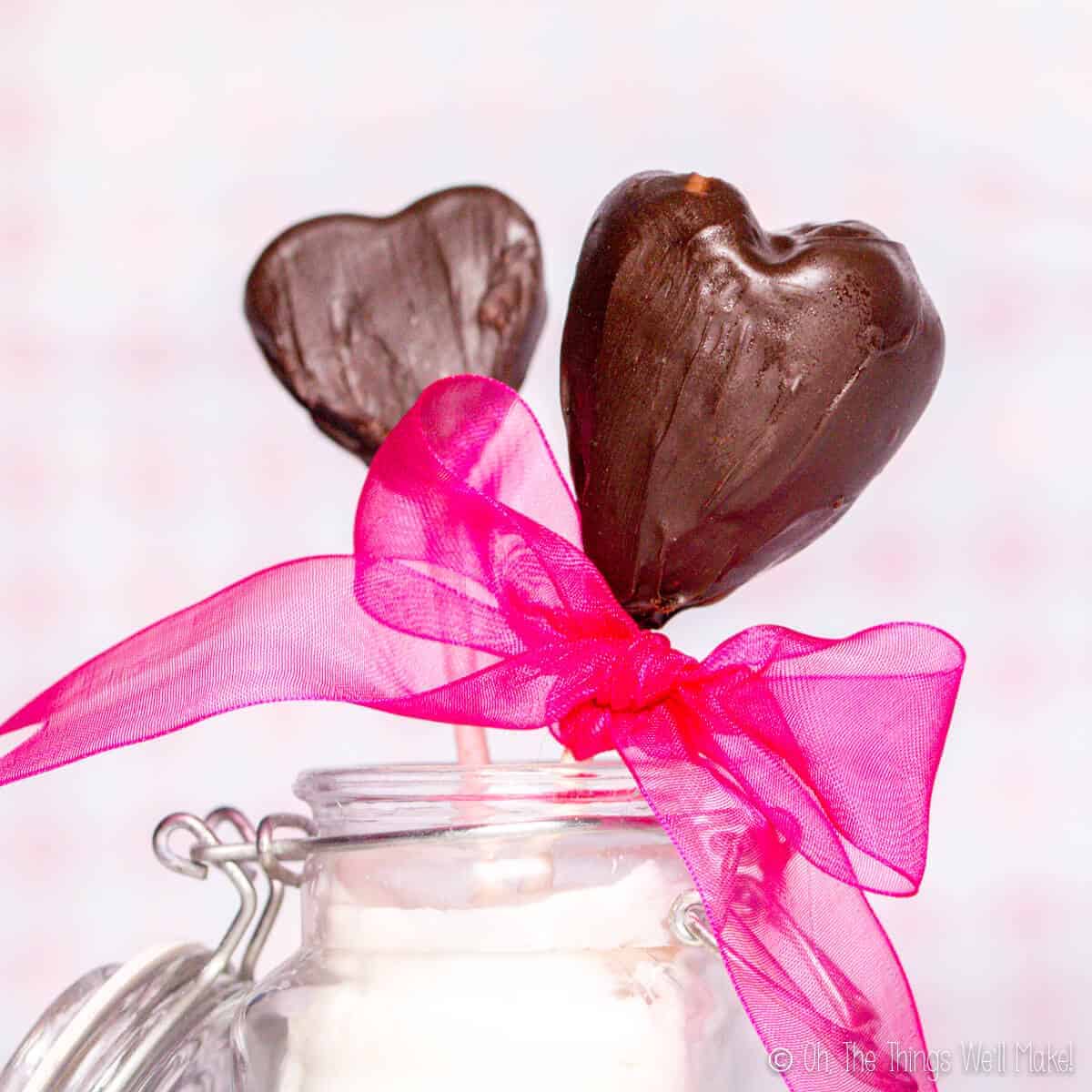 A chocolate-covered strawberry heart next to a chocolate-covered apple slice. The apple slice was first cut with a heart-shaped cookie cutter and then dipped in melted chocolate.  