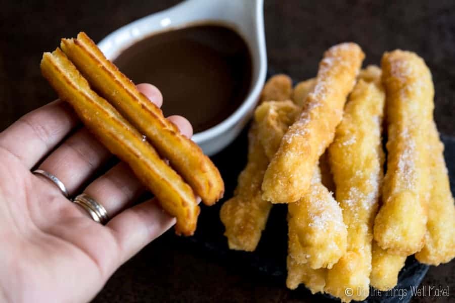 2 traditional (wheat based) churros being held next to a plate of grain-free churros.