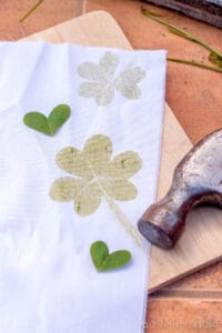 A cloth with shamrock prints and clover hearts on a wooden cutting board.
