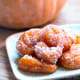 A closeup of a plate of pumpkin fritters covered with sugar.