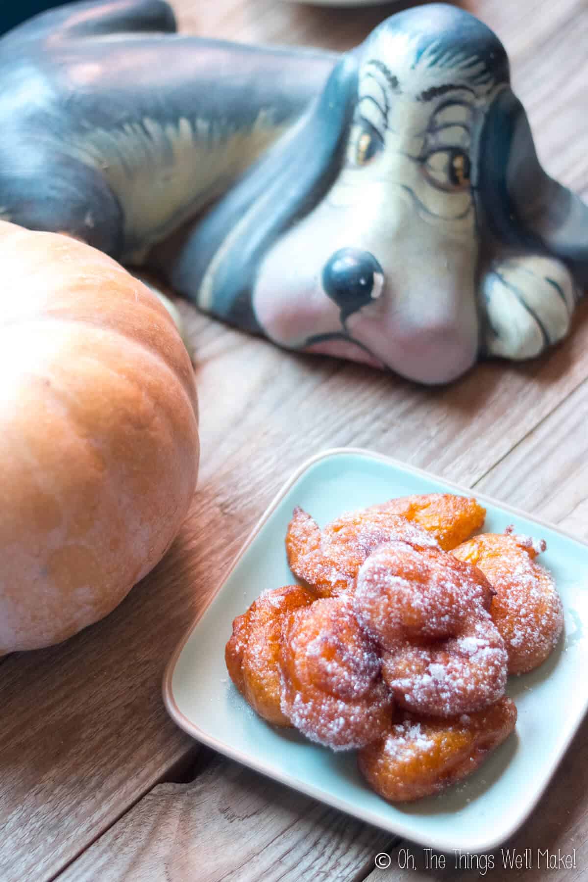 A plate of grain free pumpkin fritters with a pumpkin and a fallas "ninot" in the background