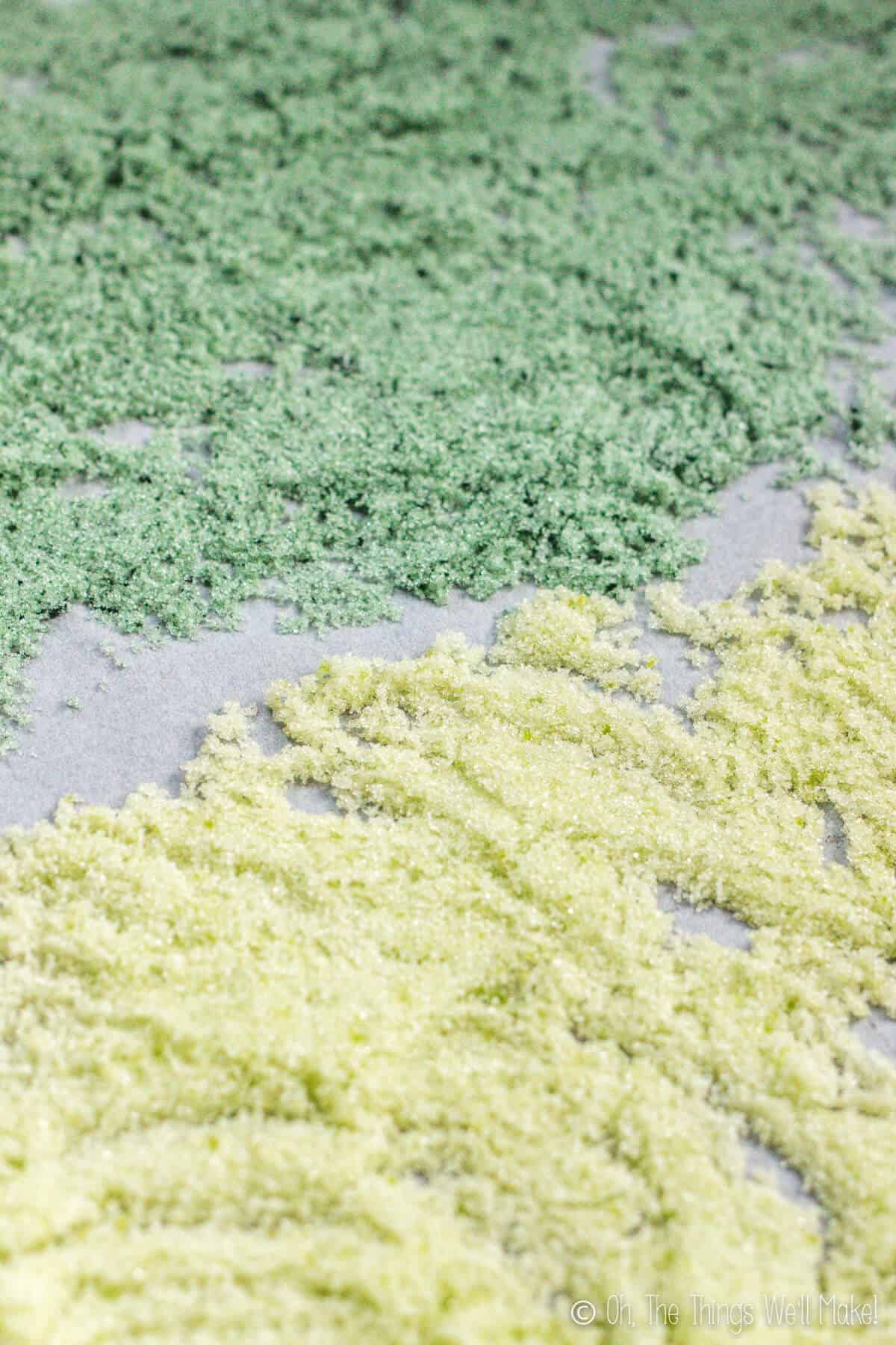 Green colored sugar crystals of 2 different shades on a parchment covered baking tray