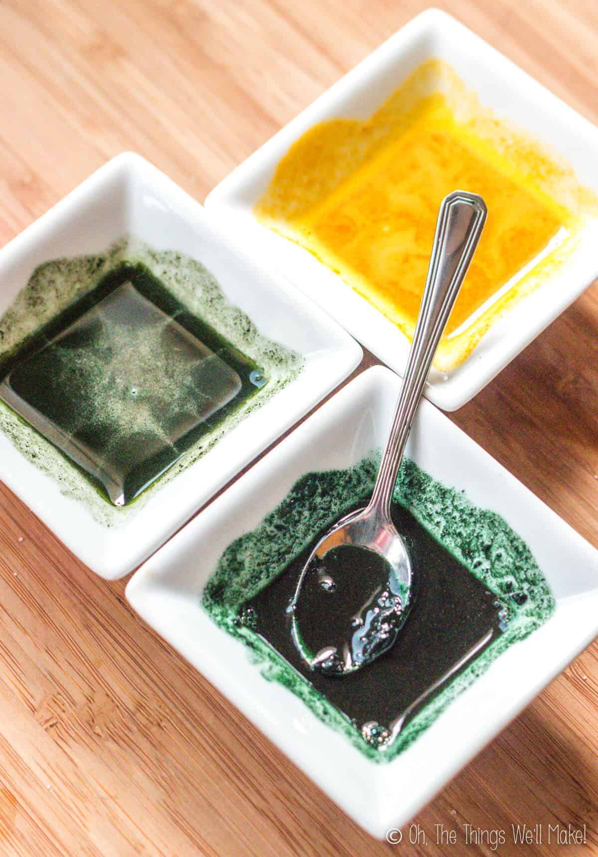 Overhead view of 2 green colorants and one yellow colorant in small white bowls