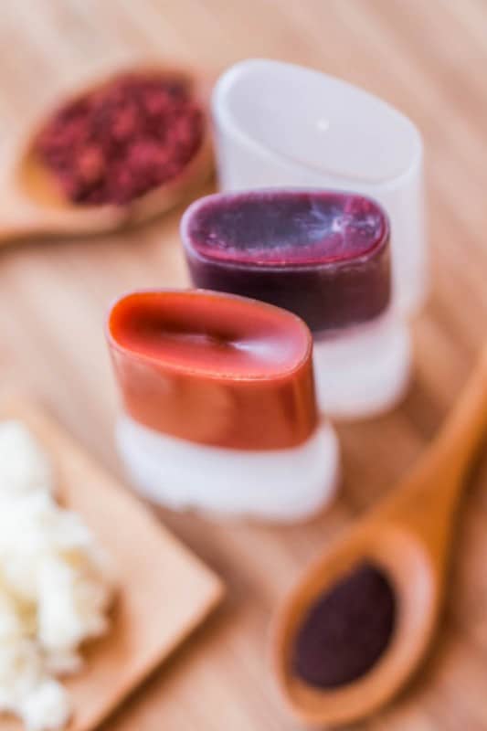 overhead view of two homemade blush sticks and alkanet root powder and annatto