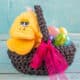 A yellow duck stuffed animal and plastic eggs inside a homemade Easter basket made from t-shirt scraps. The basket is decorated with a big pink bow.