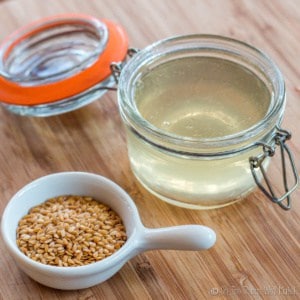 Overhead view of a jar full of homemade hair gel made out of flaxseed next to a spoonful of flaxseeds