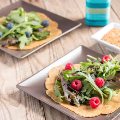 2 flaxseed tortillas on plates covered with lettuce and berries