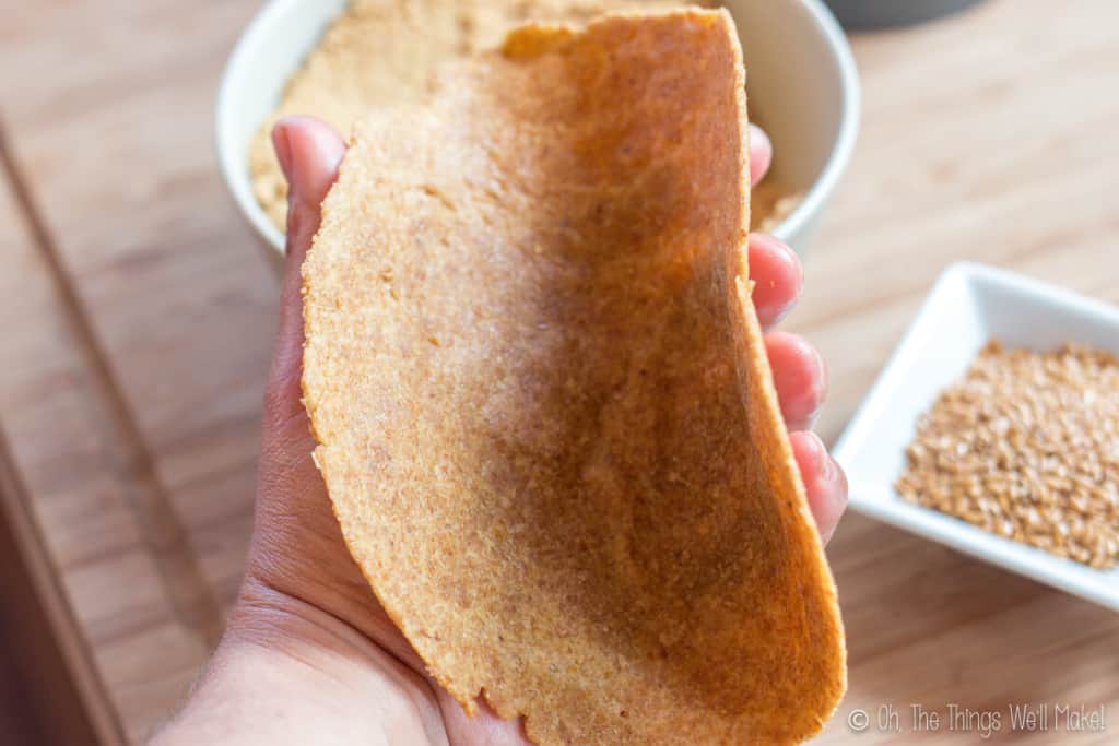 A flaxseed tortilla being bent in a way to show how pliable they are.