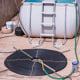 Homemade solar water heater made out of coiled black water hose laid on the ground next to a white water tank.