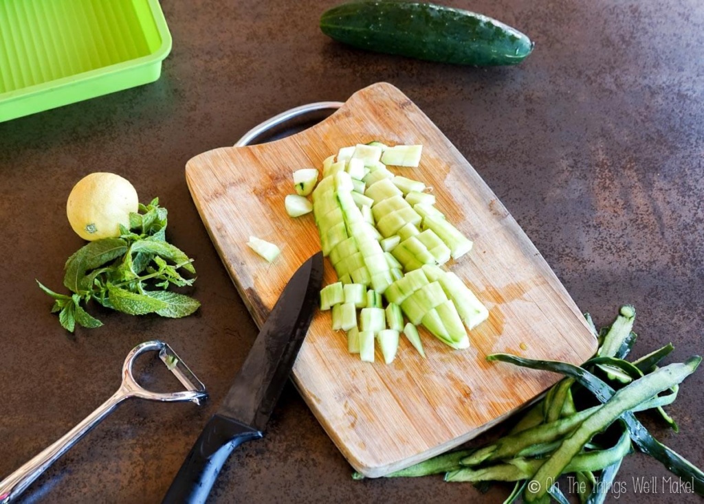 Small cucumber pieces on a bamboo cutting board.