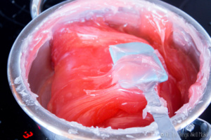 A glossy pink candy mixture for Turkish delight in a pot with a rubber spatula