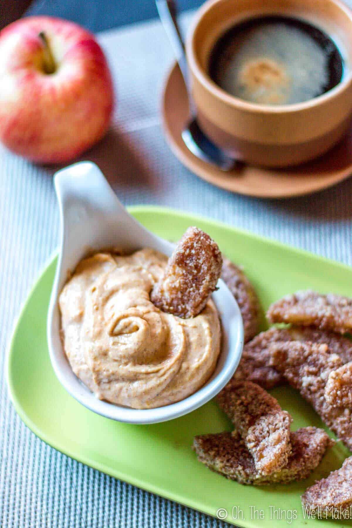 A plate of bakes apple fries with one fry dipped in a pumpkin pie dip